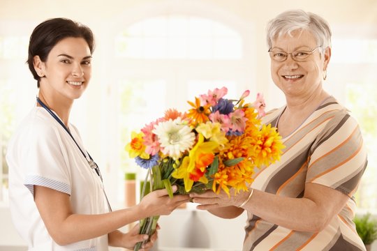 Senior Patient Giving Flowers To Nurse