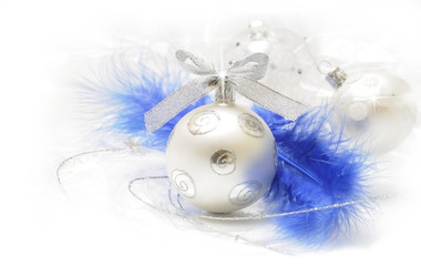 Silver christmas baubles with soft focus to feathers