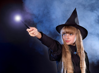 Girl in witch's hat with magic wand.