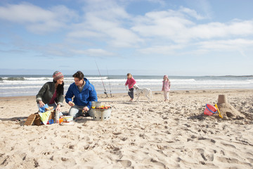 Fototapeta na wymiar Family Having Barbeque On Winter Beach