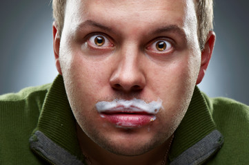 Closeup portrait of funny man. Yogurt traces on his lips
