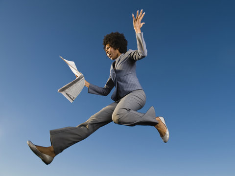 African businesswoman reading newspaper in mid-air