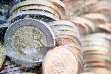 Shiny euro coins frozen in ice with german coin in front
