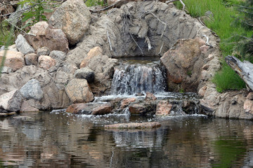 Fototapeta premium Beautiful rock waterfall flowing into a pond