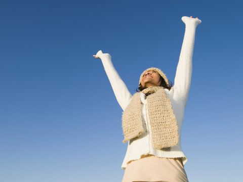 Mixed race woman smiling with arms raised