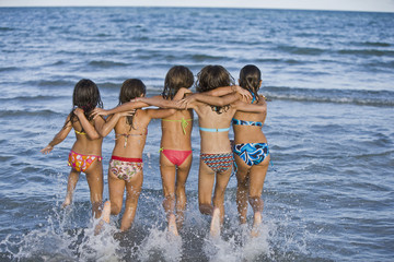 Hispanic girls running through ocean surf