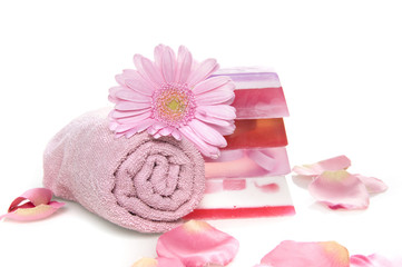 a towel, soap, a flower and rose leaves