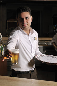 Friendly bartender serving ice cold beer