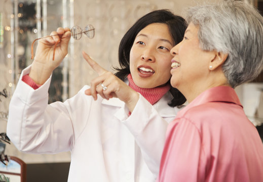 Korean optician showing eyeglasses to customer