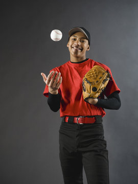 Mixed race baseball player tossing baseball