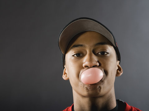 Mixed race baseball player blowing bubble with gum