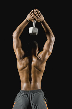 African man doing triceps extensions with dumbbell