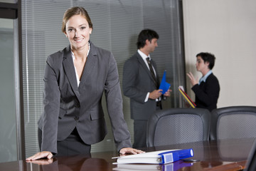 Confident businesswoman, colleagues in background
