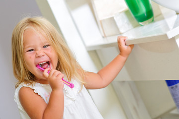 smiling girl in bathroom brushing teeth