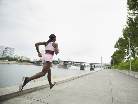 African woman running along urban waterfront
