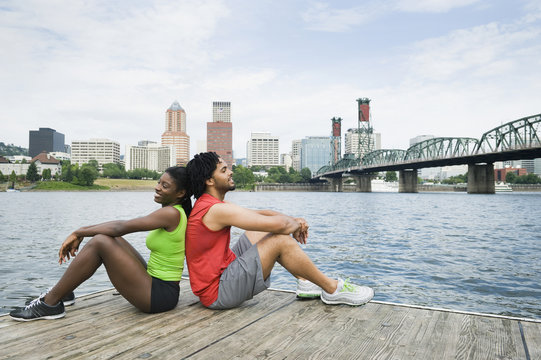 Couple sitting on urban boardwalk along river