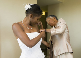 African mother helping bride with wedding dress