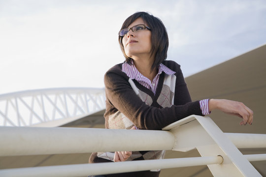 Hispanic woman leaning on urban railing