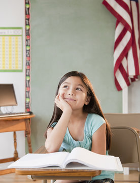 Mixed race girl daydreaming in classroom