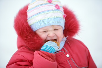 Cute girl winter portrait eating a cookie