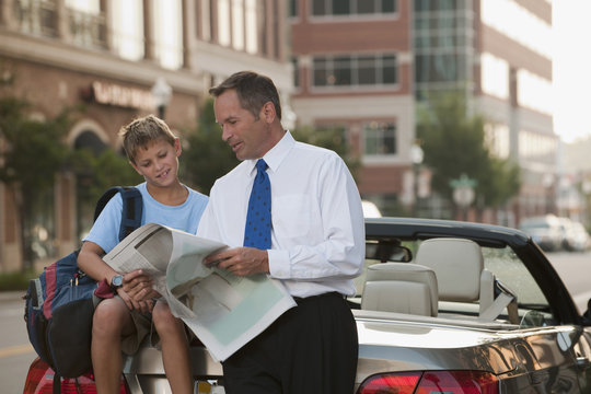 Caucasian businessman and son reading newspaper