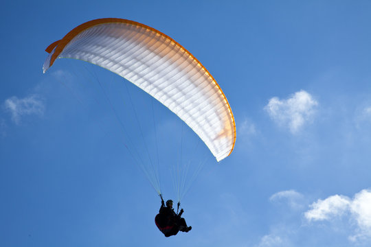Paragliding vor Wolken und blauem Himmel