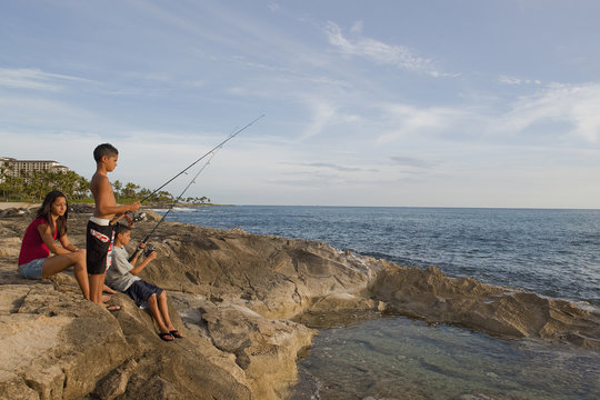 Mixed race children fishing in ocean - Powered by Adobe