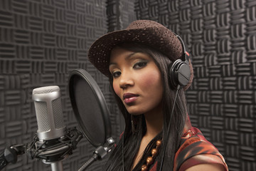 Mixed race woman singing in recording studio