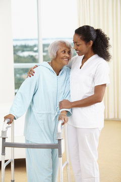 African American nurse helping senior woman with walker