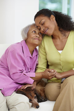 African American woman sitting on sofa with mother and dog