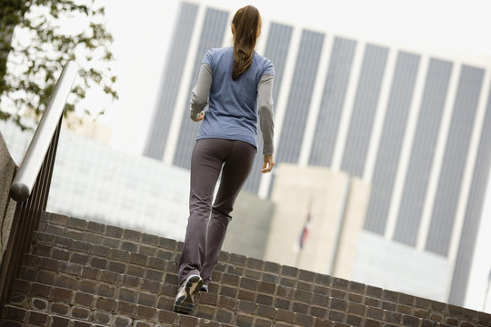 Hispanic woman running up urban steps
