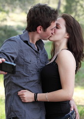 Beautiful young couple outdoors in a park taking a self-portrait