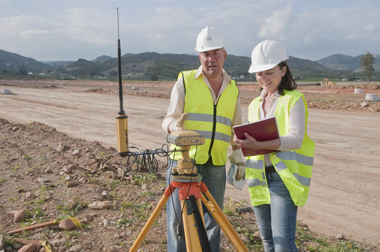 Construction workers examining equipment in field