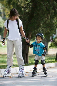 mother and son rollerskating in park