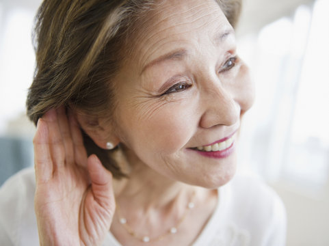 Japanese woman listening with hand near ear
