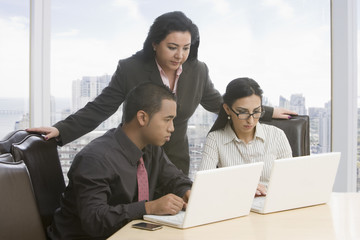 Business people in meeting using laptops