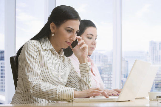 Businesswomen using laptops and cell phone