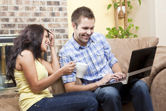 Couple sitting in living room using laptop