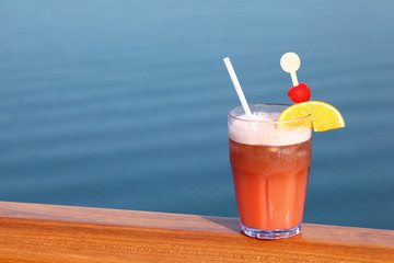 cocktail with fruits in glass on ship deck rail