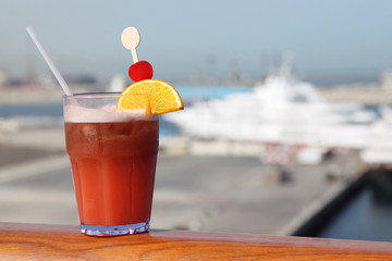 cocktail with fruits in glass on ship deck rail