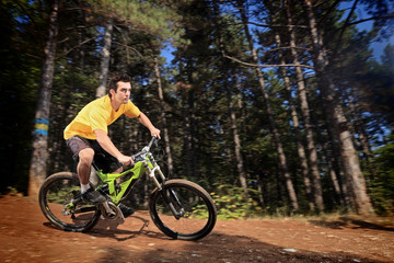 Obraz premium Young man riding a mountain bike downhill style