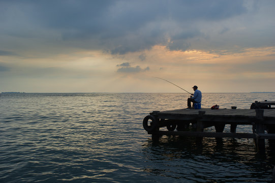 Old Man Fishing At The Dock