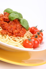 Spaghetti Bolognese on a plate with basil and cherry tomatoes