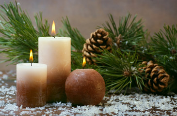 Three candles and pine branches with cones