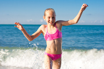 Close-up girl running from sea wave