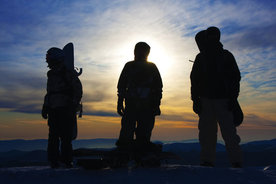 Silhouettes of the three backcountry freeriders in evening