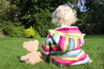 child sitting next to teddy