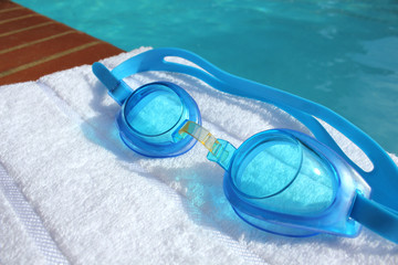 swimming goggles at the edge of a swimming pool