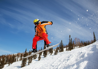 Snowboarder jumping through air with  blue sky in background