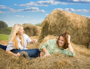 Naklejka na ściany i meble Farm girls restings on hay